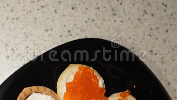 红鱼子酱是用勺子放在带有干酪的小馅饼上用红鱼子酱准备零食上景框架视频的预览图