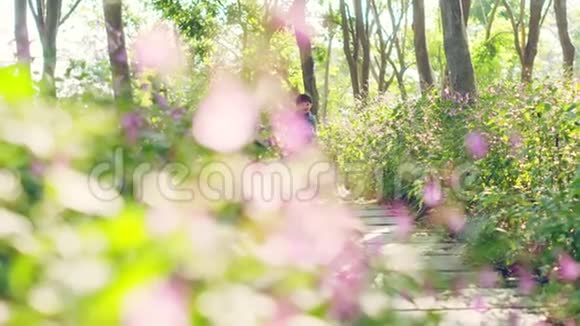 两个亚洲小孩在公园的花田里奔跑视频的预览图
