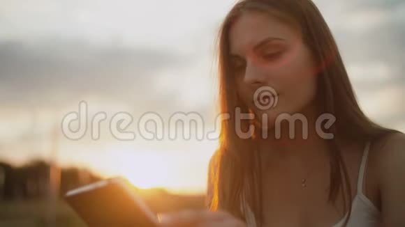 在公园里看电子书的年轻女子夕阳西下视频的预览图