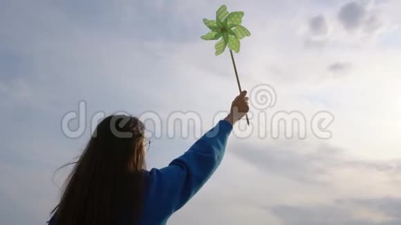 女孩在天空的背景下手握着风车视频的预览图