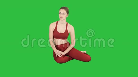 漂亮的健身女人坐在地板上听绿色屏幕Chroma键视频的预览图