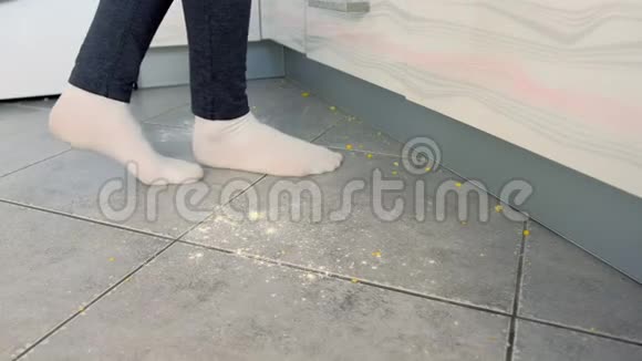 女人在厨房的肮脏地板上剩菜和面包屑掉在厨房地板上穿着白色袜子的腿视频的预览图