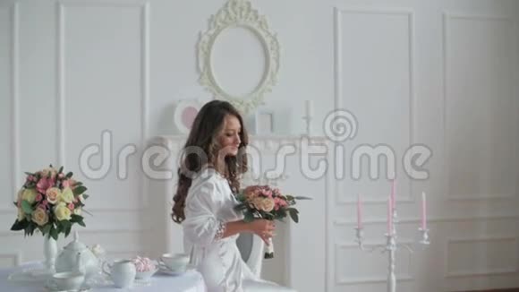 穿着浴袍的美女看着婚礼花束视频的预览图