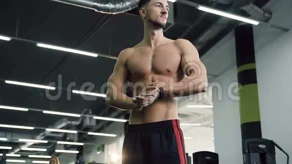 漂亮的年轻人没有t恤他的手在健身房的背景上摩擦视频的预览图