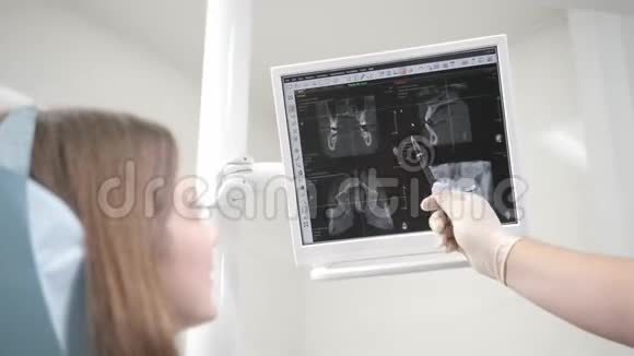 医生在监视器上显示了x射线的照片一个年轻漂亮的女孩坐在牙医椅上的画像视频的预览图