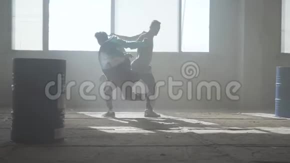 训练熟练的街舞者两个成功舞者的朋友正在一座废弃的尘土飞扬的建筑里跳舞视频的预览图