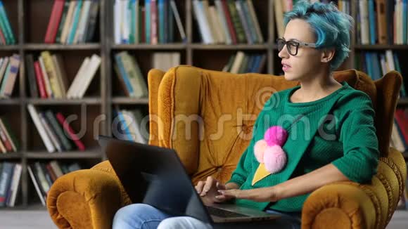 在图书馆里用笔记本电脑打字的时髦女孩视频的预览图
