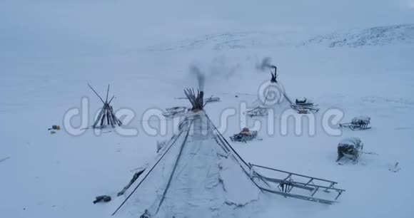 无人机在北极中部的傍晚捕捉蒙古包的特写镜头蒙古包外有许多雪橇视频的预览图