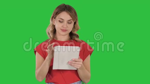 微笑的女人与平板电脑呈现翻页的绿色屏幕铬键视频的预览图