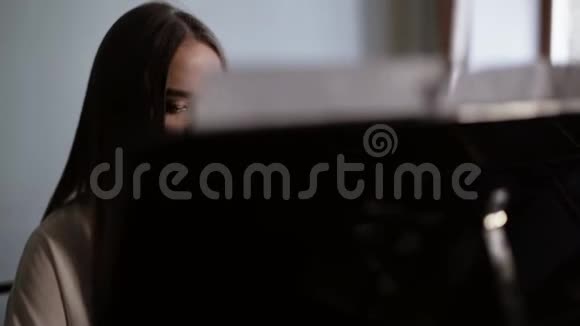 女钢琴家在一架大型钢琴上缓慢地演奏古典音乐视频的预览图