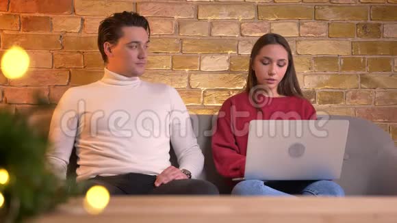 男人和女人把他们的笔记本电脑和智能手机放在更近的地方在舒适的家庭氛围中开始愉快的交流视频的预览图