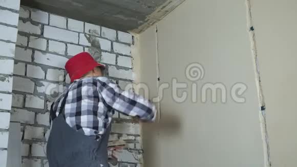 男建筑工人在工作时穿着用石膏填补墙上的空隙有自由的空间视频的预览图