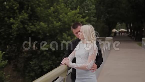 幸福的爱情夫妻站在城市公园的铁桥上拥抱视频的预览图
