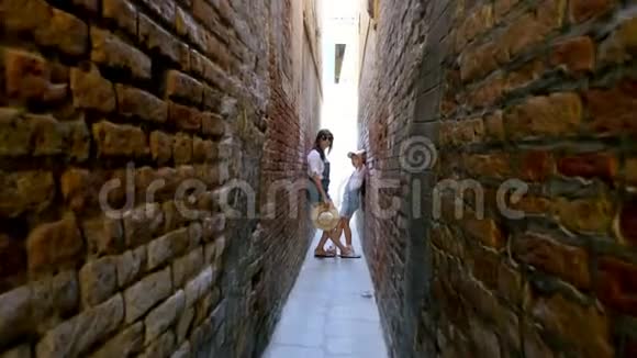 威尼斯意大利2018年7月7日在威尼斯非常狭窄的街道上在旧房子的墙壁之间站着一个十几岁的女孩孩子视频的预览图