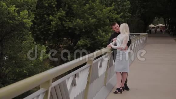 幸福的爱情夫妻站在城市公园的铁桥上拥抱视频的预览图