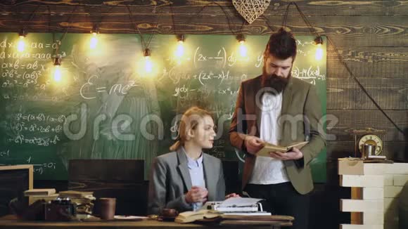 古典风格的教师一个长胡子的男人读一本书而一个女人则在一台木制背景的打字机上打印文本视频的预览图