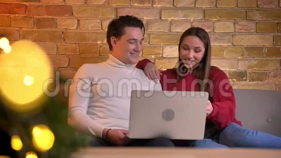 在家里的气氛中一副开朗的白种人朋友看着笔记本电脑在沙发上大笑的特写视频的预览图