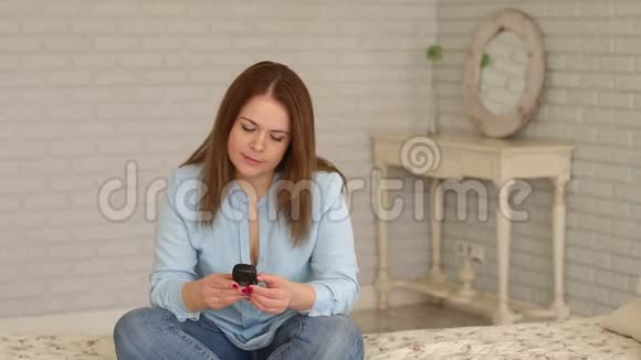 一位患有糖尿病的妇女坐在家里的床上手里拿着血糖仪视频的预览图