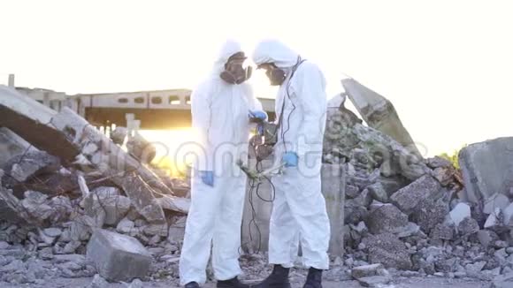 两名穿着防护服和面罩的科学家在废墟的背景下测量了辐射视频的预览图