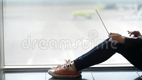 聪明而放松的女人坐在窗户附近在笔记本电脑上输入信息视频的预览图