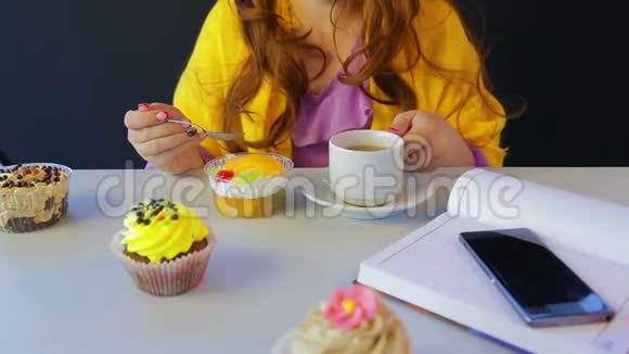 在餐桌旁的咖啡馆里女孩喝茶用勺子吃蛋糕视频的预览图