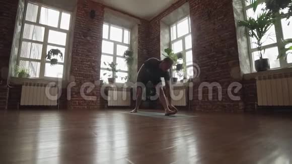 做一个体式的年轻人城市工作室黑色垫子上的瑜伽大师练习视频的预览图