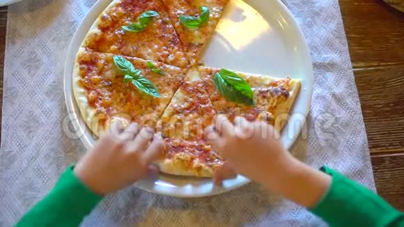 儿童的手拿着一片比萨饼从一个白色盘子在餐厅咖啡馆特写镜头小男孩小女孩吃披萨视频的预览图