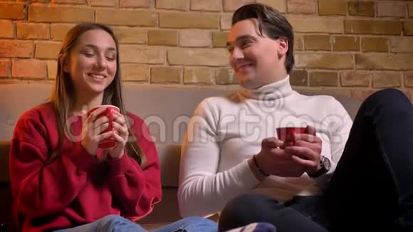 两位年轻的白种人朋友在沙发旁喝茶在舒适的家里互相交谈他们的特写照片视频的预览图