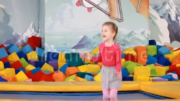小女孩在蹦床上玩耍和跳跃孩子们在操场上玩耍和跳跃视频的预览图