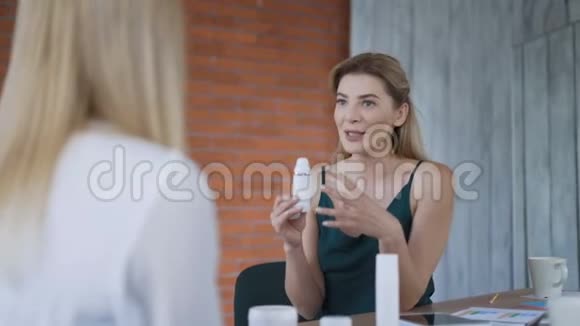 两个商界女性朋友在办公室谈论化妆品女孩尝试新的化妆品并评估结果4K视频的预览图
