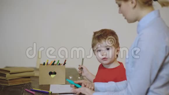 男孩和他的母亲画在一张桌子上孤立的白色背景亲近快乐的小男孩视频的预览图