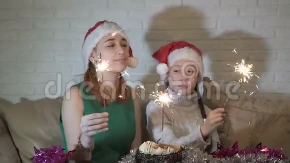 圣诞老人的帽子上戴着亮闪闪的快乐的孩子们坐在蛋糕旁边的沙发上微笑着视频的预览图