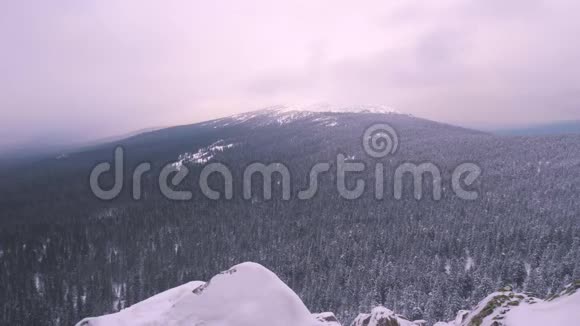 一个背着背包的年轻人站在一座白雪覆盖的山上欣赏着风景视频的预览图