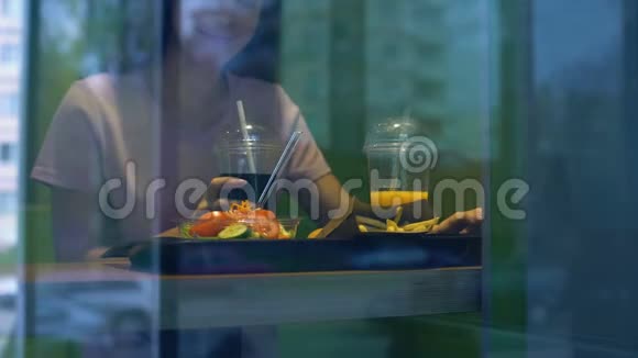 年轻的微笑女人品尝软饮料在快餐店吃午餐视频的预览图