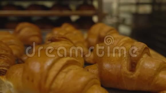 托盘上摆着许多美味新鲜的牛角面包生产糕点和面包背景视频的预览图