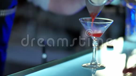 酒保通过鸡尾酒过滤器将混合利口酒倒入准备好的玻璃杯中视频的预览图