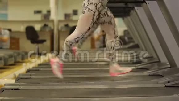 那个女孩在健身房的跑步机上跑步健身理念特写镜头视频的预览图