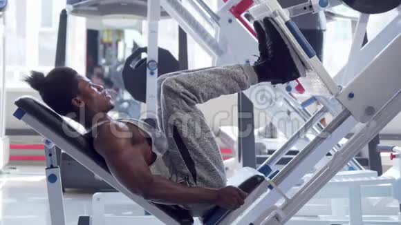 肌肉非洲健身者在健身房用压腿机锻炼视频的预览图