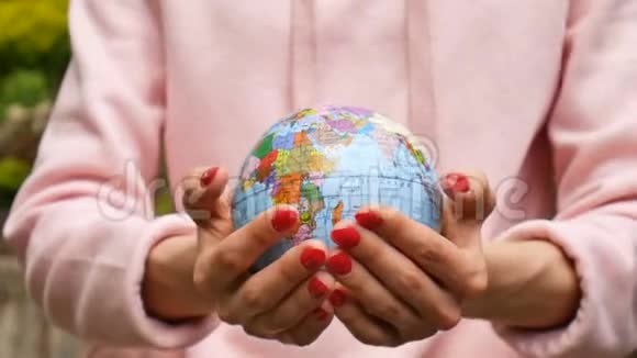 用红色指甲特写女性手的视频用乌克兰的西里尔语给出一个带有地理特征名称的小地球仪视频的预览图