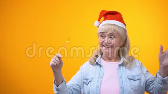 乐观的老年女士带着孟加拉灯跳舞庆祝圣诞前夜背景视频的预览图