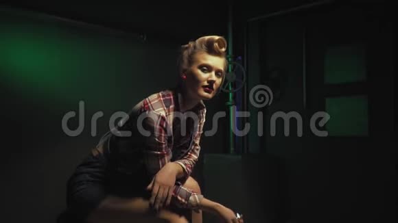 热辣的女工下班后坐着手里拿着一把扳手深绿色的背景视频的预览图