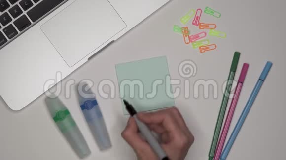 女人在粘合剂记事本上写BLOG桌上的笔记本和文具视频的预览图