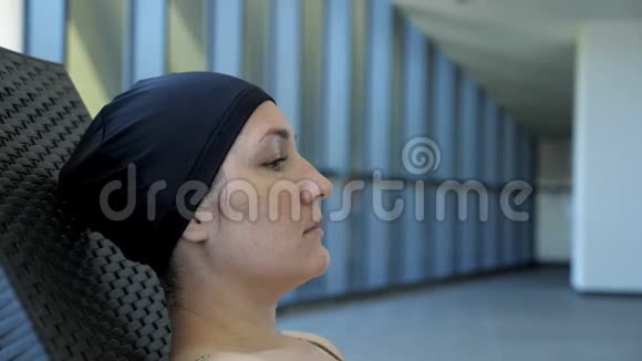 戴帽子的女人在游泳池里游泳后正在躺椅上休息视频的预览图