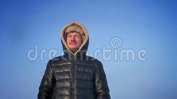 绕着兜帽里的中年探险家在雪地上乐观地看着太阳视频的预览图
