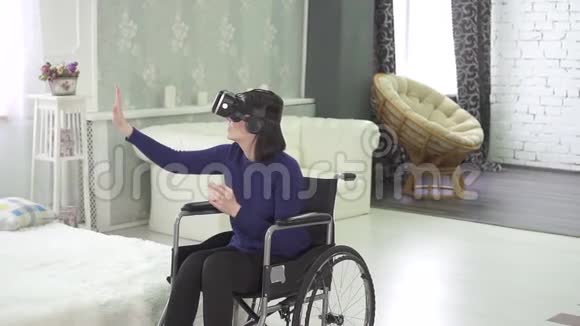 轮椅上的年轻残疾妇女戴着虚拟头盔利用3D技术在互联网上工作视频的预览图