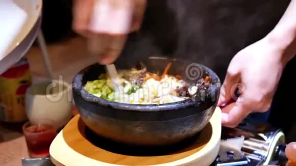 服务员在餐桌上为顾客搅拌韩国bibimbap的动作视频的预览图