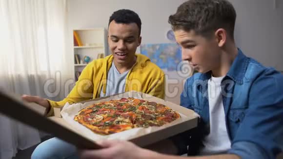 两个多种族的朋友打开盒子为学生聚会准备披萨视频的预览图