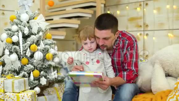 关爱的父亲教蹒跚学步的女儿在圣诞节画画视频的预览图