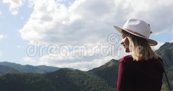 年轻女子徒步旅行者戴着帽子欣赏着山谷中令人惊叹的景色视频的预览图