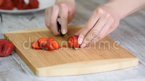 一只雌性手在木板上切割草莓草莓切片视频的预览图